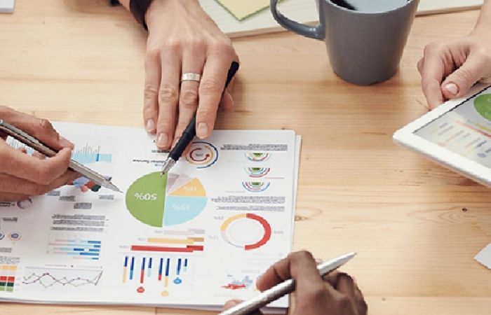Hands of people around table discussing report with graphs